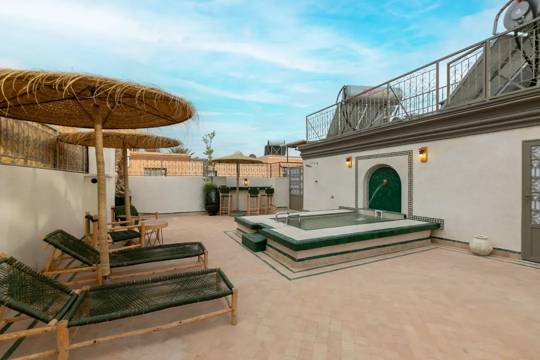 Rooftop terrace with a green-tiled plunge pool, wall fountain and reed parasols